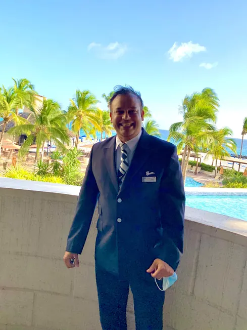 Sabbir Karim in British Airways uniform on a terrace overlooking palm trees and the sea