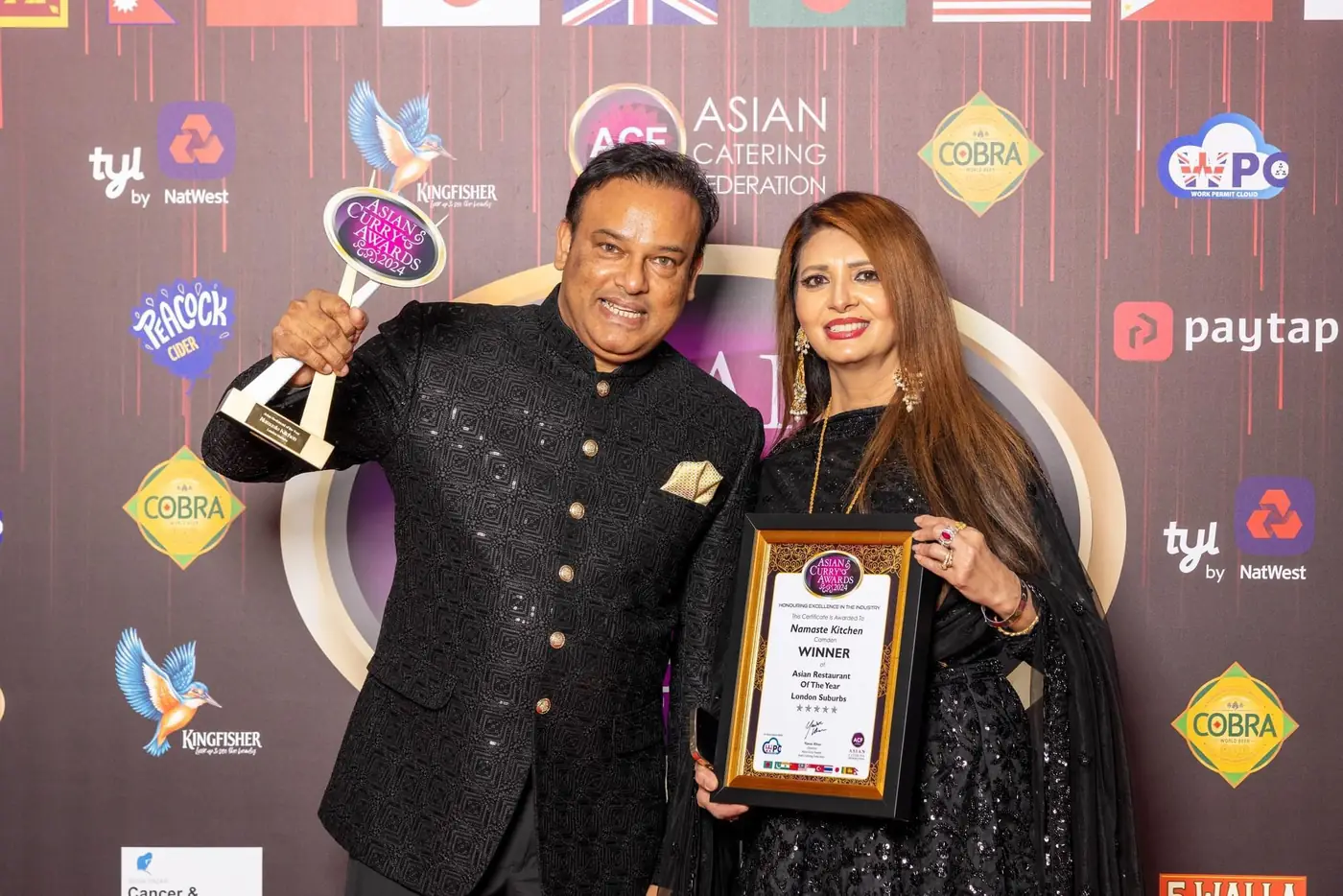 Sabbir Karim holding a trophy at the Asian Curry Awards in front of a sponsor wall