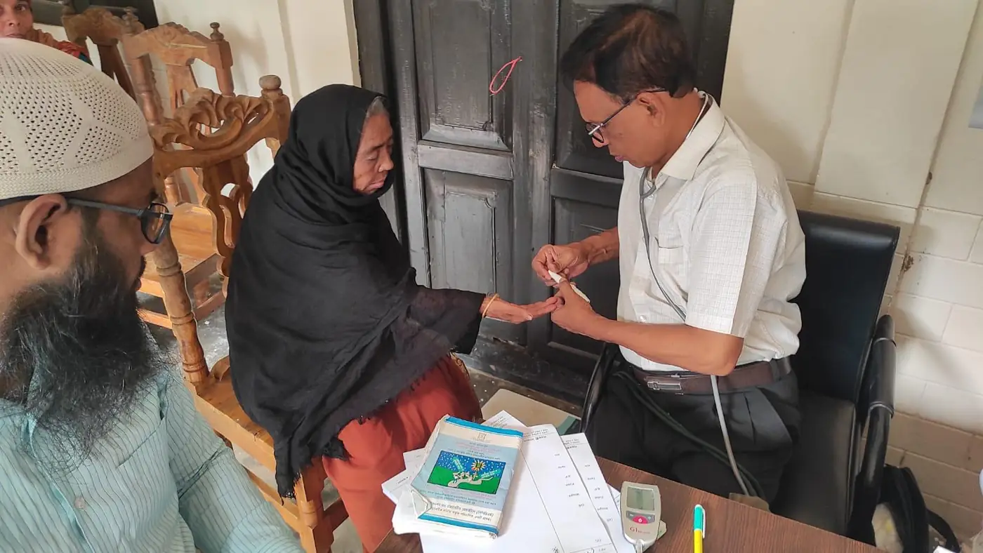 A doctor checking a patient&rsquo;s blood sugar at a free clinic in Bangladesh