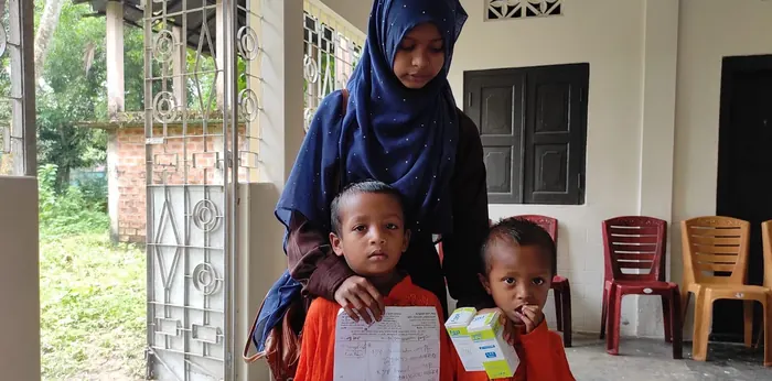 Two young children holding a prescription and a box of medicine