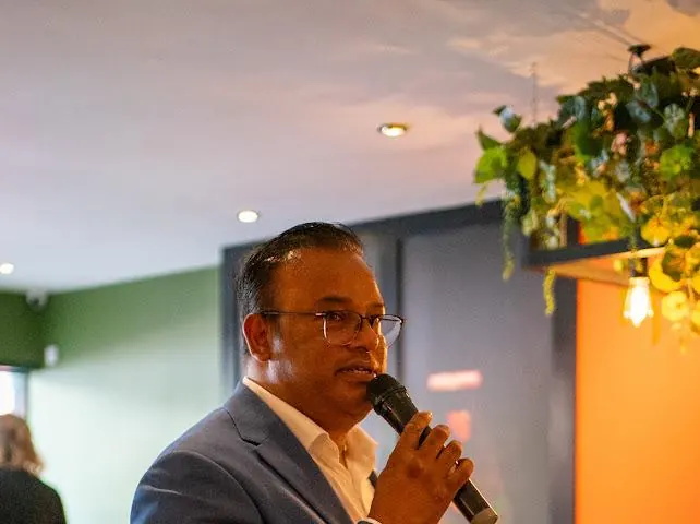Sabbir Karim speaking into a microphone at a community event