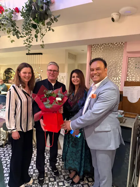 Sabbir Karim with guests holding a bouquet at one of his restaurants